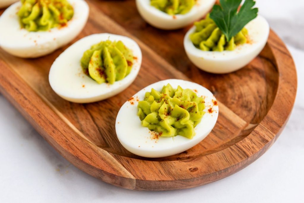 Avocado deviled eggs on a wooden board.