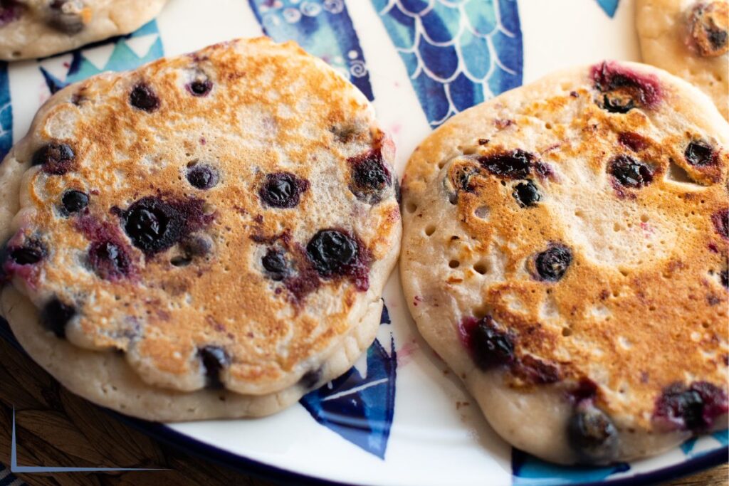 Blueberry Almond Pancakes on a white and blue plate.