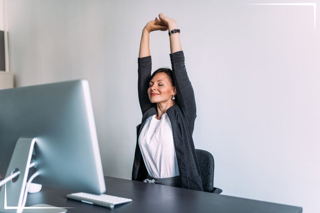 A woman stretching at her desk.