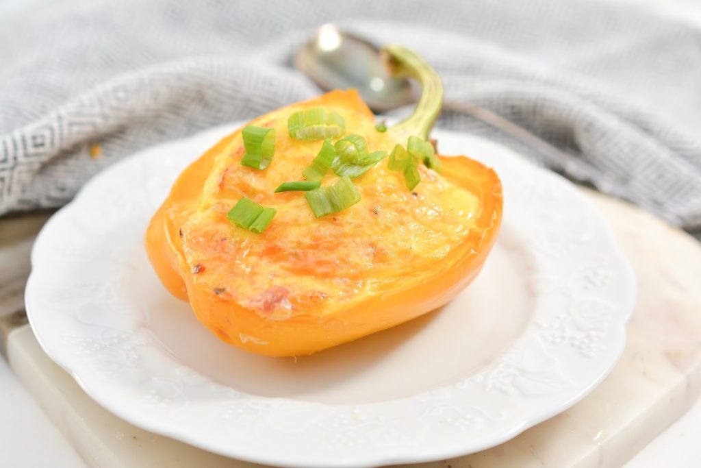 An omelette stuffed pepper on a white plate.