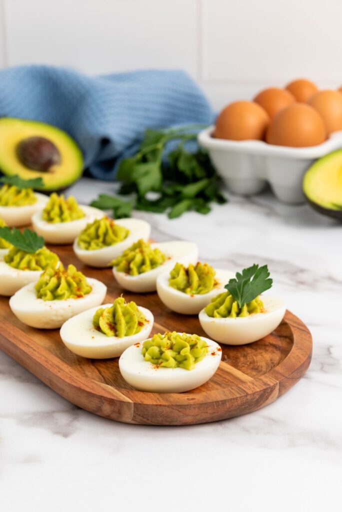 Avocado deviled eggs on a wooden board.