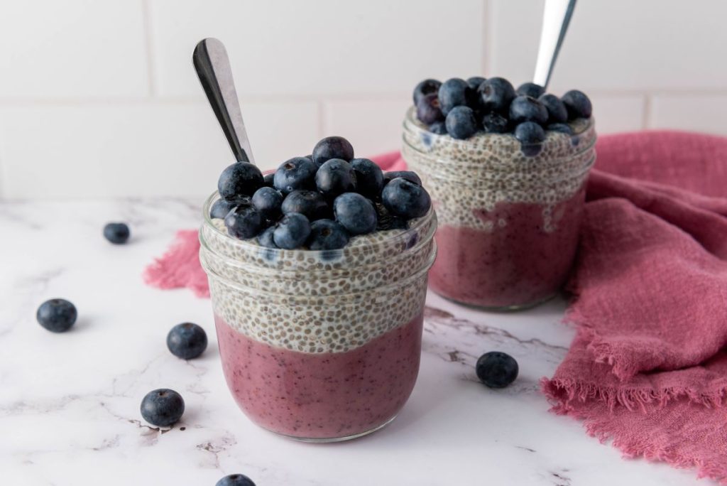 Layered blueberry chia pudding in two mason jars.