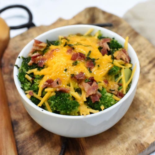 Loaded broccoli in a bowl on a cutting board.