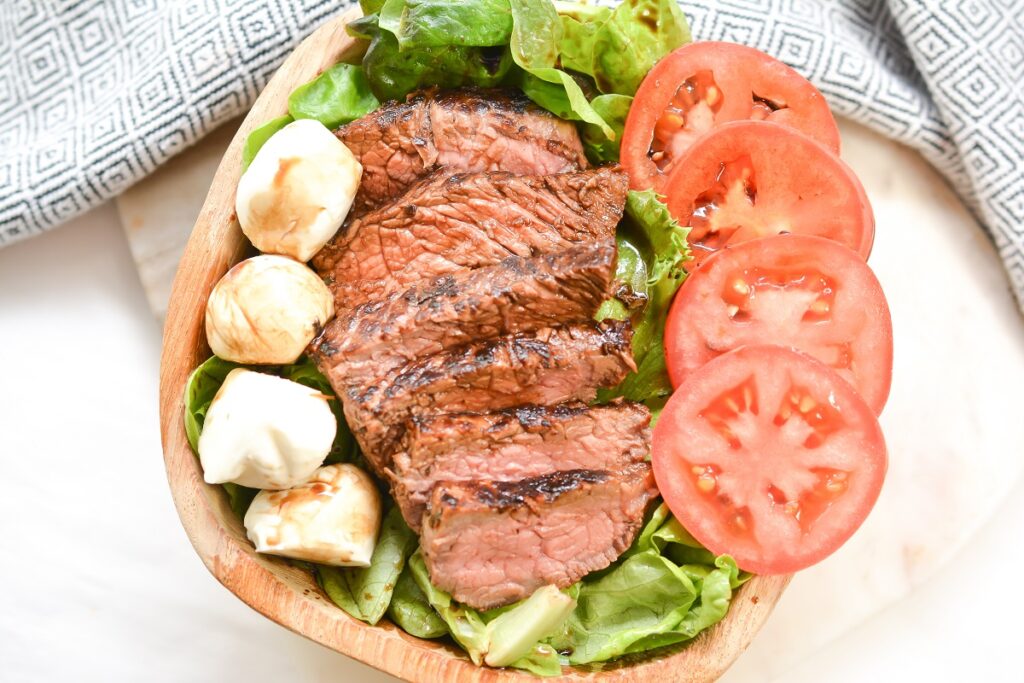 Steak Caprese Salad in a wooden bowl.