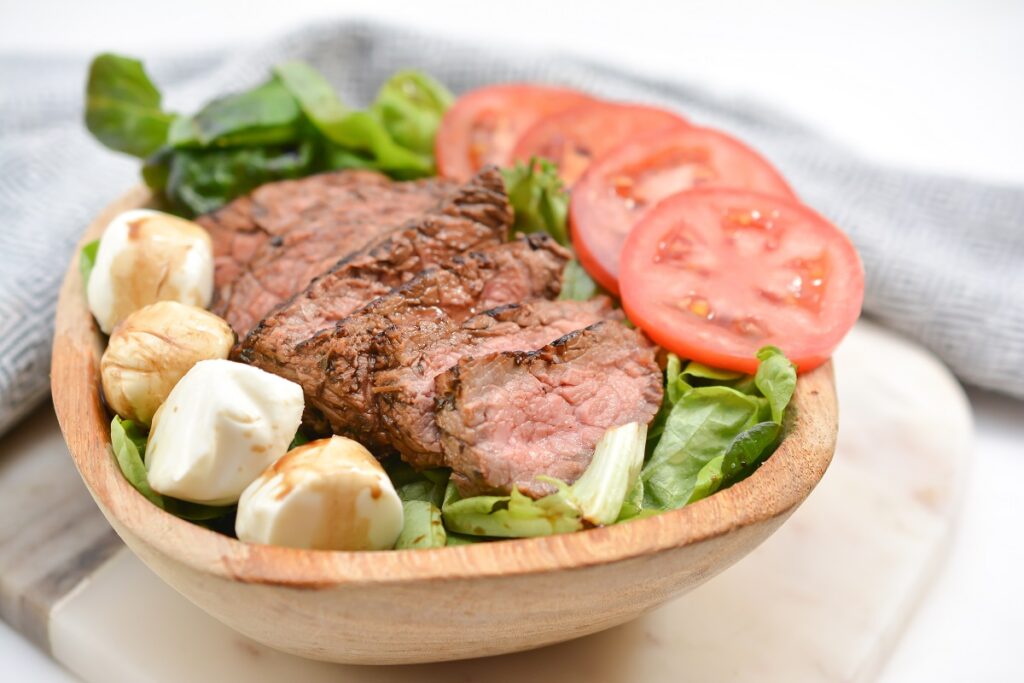 Steak Caprese Salad in a wooden bowl.