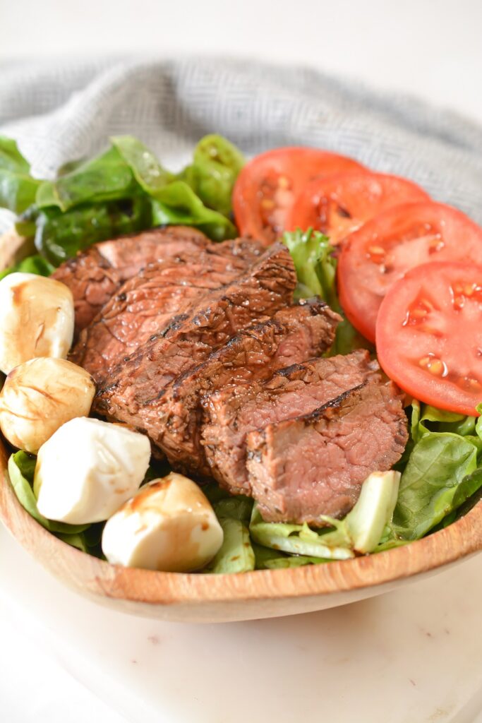 Steak Caprese Salad in a wooden bowl.